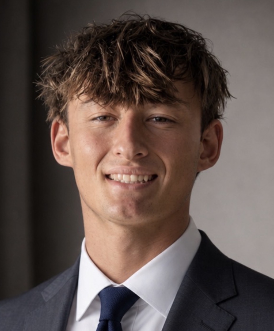 Dylan Brown, headshot in a navy suit.